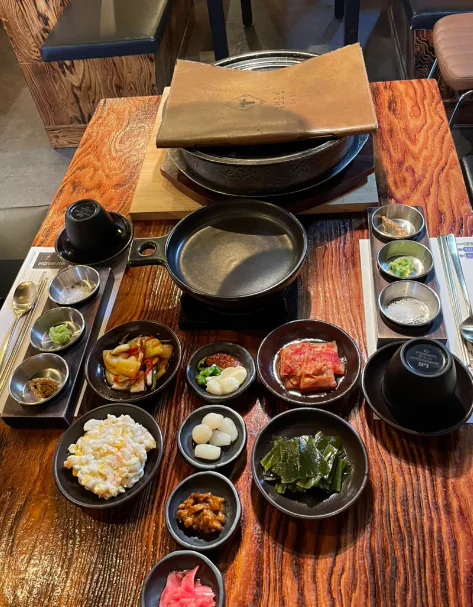 A table with the grill covered and the side dishes laid out