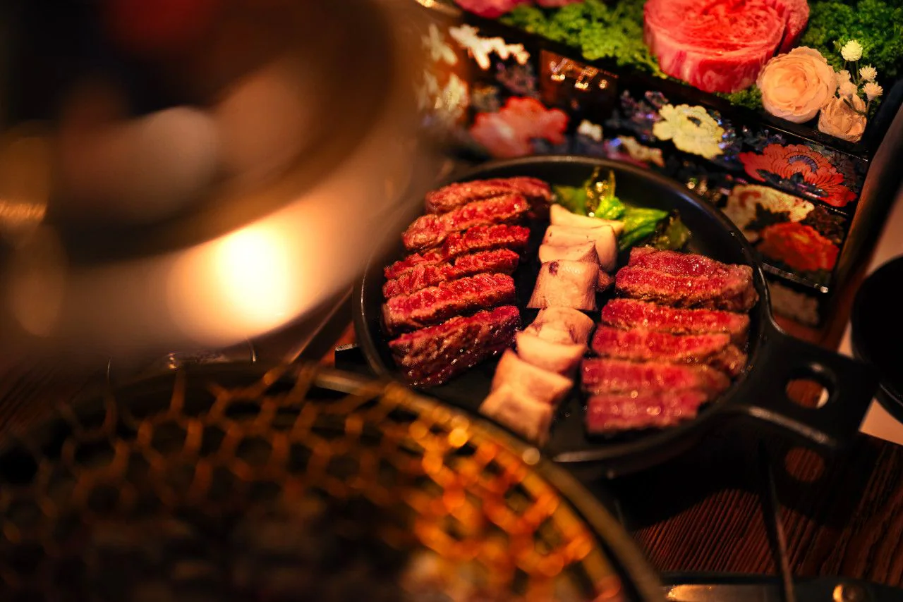 Grilled Hanwoo in a cast-iron pan with a black lacquer box behind