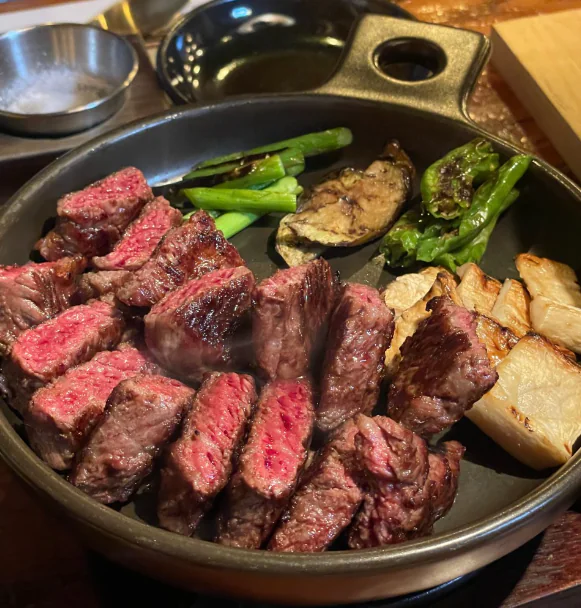 Grilled Hanwoo in a cast-iron pan with a black lacquer box behind